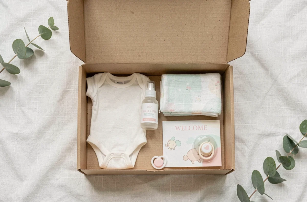 Vue à plat d'un coffret naissance gratuit ouvert avec des produits essentiels pour nouveau-né soigneusement disposés